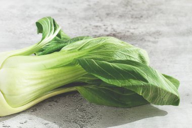 Taze bok choy, açık gri bir yüzeye serilmiş, üst manzara, doğal ışık.,