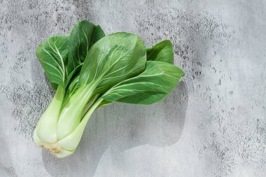 Taze bok choy, açık gri bir yüzeye serilmiş, üst manzara, doğal ışık.,