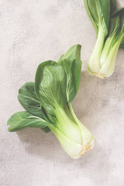 Taze bok choy, açık gri bir yüzeye serilmiş, üst manzara, doğal ışık.,