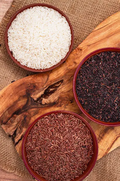 Kırmızı, siyah ve beyaz pirinç seti, bir kâse içinde, ahşap bir yüzey üzerinde, kırsal tarzda, üst manzara