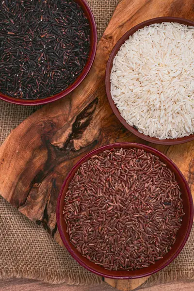Kırmızı, siyah ve beyaz pirinç seti, bir kâse içinde, ahşap bir yüzey üzerinde, kırsal tarzda, üst manzara