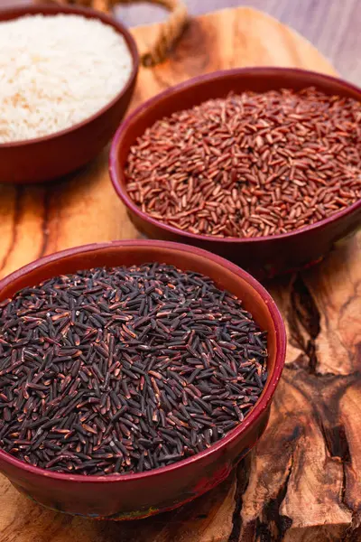 Kırmızı, siyah ve beyaz pirinç seti, bir kâse içinde, ahşap bir yüzey üzerinde, kırsal tarzda, üst manzara