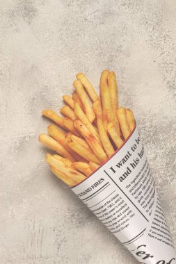 Soyut bir arka planda kızarmış patates kızartması. İnsanlar olmadan, köy usulü bir pakette, gazete külahında, gazete poşetinde.,