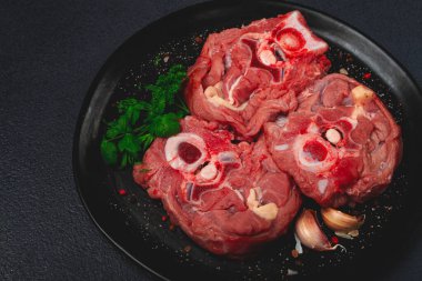 Çiğ biftek, kemikte dana boynu, taze et, siyah tabakta, üst manzara, insan yok.,