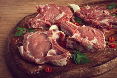 Çiğ dana eti, kemikte et, barbekü için et, kesme tahtası, baharatlar ve otlarla, üst görünüm,