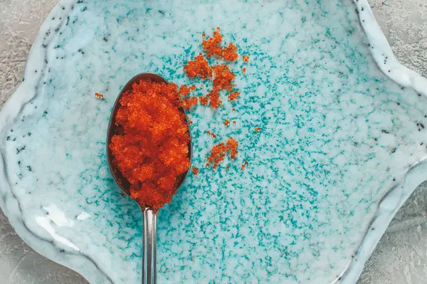 Turuncu uçan balık havyarlı bir kaşık, Tobiko, açık mavi bir tabakta, havyar rulo ve suşi için, yakın plan.,
