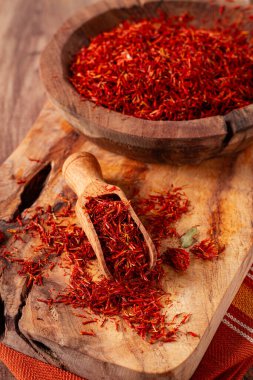 Baharat safranı iplikleri, ahşap bir kasede, ahşap bir masanın üstünde, üst manzara, yakın çekim.,