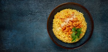 Karidesli risotto, bir kasede, dokulu bir yüzeyde, yanında taze kişniş tabağı, ev yapımı, insan yok.,