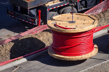 Büyük kırmızı kablo bobini, şehir inşaatında kurulum için yükseliyor, insan yok.