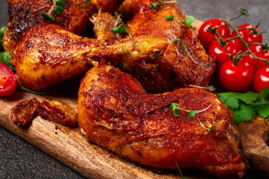 Kızarmış tavuk bacağı, taze kiraz domatesleri ve ahşap kesim tahtasıyla servis edilen otlar, ev yapımı, insan yok.,