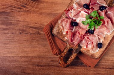 Kesme tahtasında dilimlenmiş jambon, zeytin ve otlarla, atıştırmalık, kahvaltı, insan yok.,