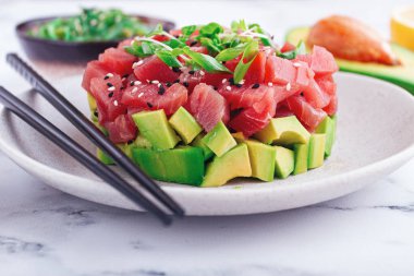 Soya sosu ve yosun salatasıyla mermer masada servis edilen avokado ile taze ton balığı.