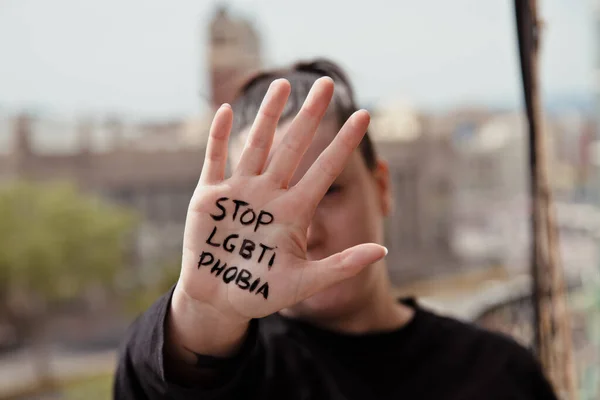 Girl has a hand in front of her with a message written on the palm of her hand stops lgtbphobia