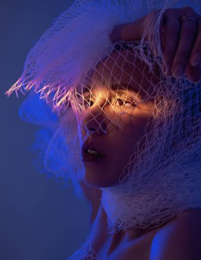 Palmiye yapraklı kadın oturuyor, mavi ve sarı ışık parlıyor.