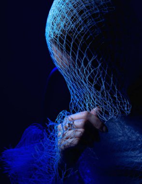 Mavi ışığa sarılmış bir kız yüzünü saklar 