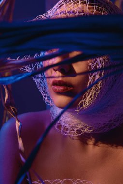 Kırmızı ışığa sarılmış bir kız yüzünü saklar.