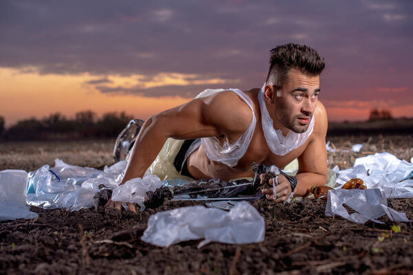 спортивный человек с атлетической фигурой, завернутый в пластик на земле