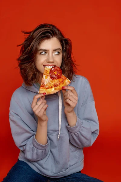 stock image a young girl on an orange background in casual clothes bites a p