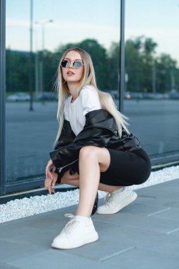 Deri ceketli ve siyah tişörtlü genç bir sarışın. 