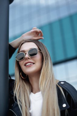 Deri ceketli ve alışveriş merkezinin yanında siyah gözlüklü güzel bir kız.