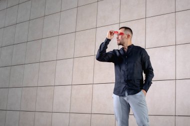 Açık renk pantolonlu şık bir adam ve sırtında siyah bir gömlek.