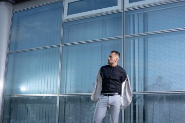 Açık renk pantolonlu şık bir adam ve sırtında siyah bir gömlek.