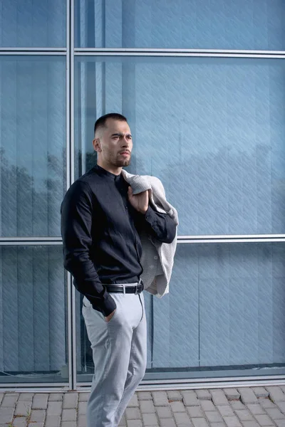 stock image a stylish man in light pants and a black shirt against the backg