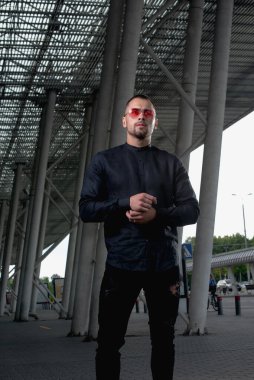 Açık renk pantolonlu şık bir adam ve sırtında siyah bir gömlek.