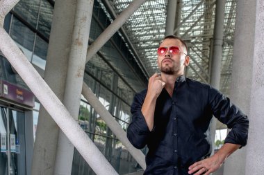 Açık renk pantolonlu şık bir adam ve sırtında siyah bir gömlek.