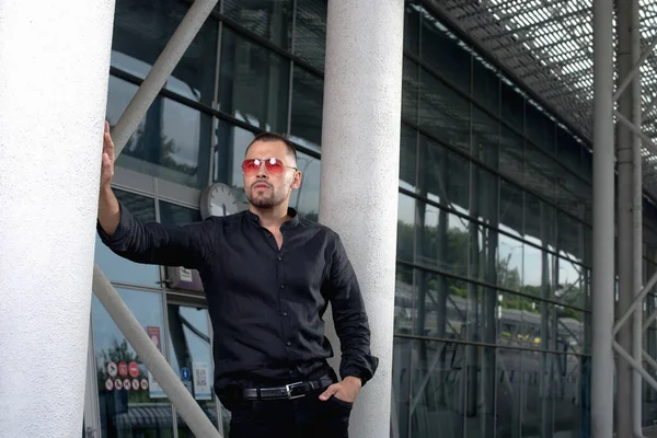 stock image a stylish man in light pants and a black shirt against the backg