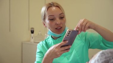 Kozmetik ameliyattan önce doktor cep telefonuyla fotoğraf çekiyor. Güzellik merkezinde cilt bakımı yapan bir dermatolog.