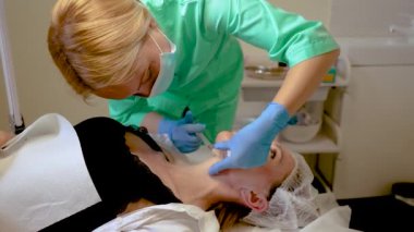 Yaşlı kadın güzellik salonunda nörotoksin iğnesi yaptırıyor, yaşlanma önleyici cilt tedavisi. Profesyonel kozmetik uzmanı cilt yenilenmesi için nörotoksin enjekte ediyor. Çekici bayan hasta.