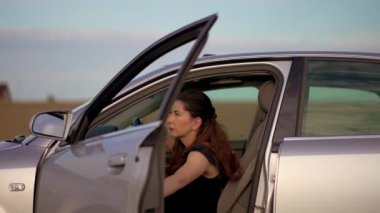 Sıkıntılı üzgün kadın bozuk arabanın kapısını açtı ve kırsal yoldaki motor arızasını incelemek için dışarı çıktı. Acil durum sigortası olan kadın yolda. Stres tehlikesi var.