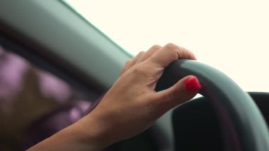 Yoldaki direksiyonda kadın eli olan birinin yan görüntüsü. Yetişkin bir kız güvenli bir şekilde araçla işe gidiyor.