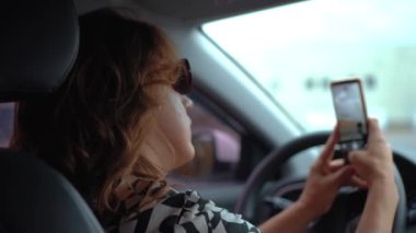 Arabadaki kadın sosyal medyada paylaştığı için akıllı telefondan fotoğraf çekiyor. Otomobil içinde cep telefonu olan bir kadın