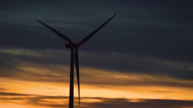 Rüzgâr türbini, dramatik bulutlu pembe turuncu günbatımının arka planında dönen bıçaklar. Ekoloji Güvenli Alternatif Enerji Kaynağı. Yeşil ekolojik dünya için yenilenebilir enerji üretimi