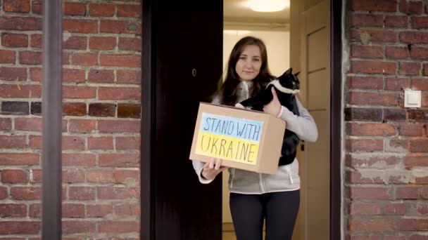 乌克兰难民妇女与她心爱的猫一起 在临时庇护所门口 带着人道主义援助从志愿者手中接过的盒子 帮助乌克兰与俄国的侵略作战 — 图库视频影像