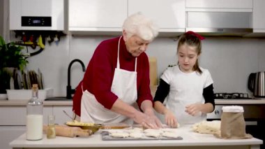Mutfakta beyaz bir aile var. Büyükannesi ve kızı hamur mayasını doldurmuş. Beyaz una batırılmış parçalar. Evdeki modern mutfakta pasta ya da pasta pişirmek.