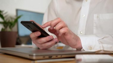 Analiz ve analiz. İşçi ev ofisinde çalışırken modern akıllı telefonu elinde tutuyor, iş yerindeki telefonu kapatıyor. Erkek Freelancer evden çalışıyor. İnternet taranıyor, sosyal kullanılıyor