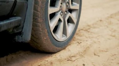 Pahalı krom jantlı lüks araba kumlu yol boyunca gidiyor. Kirli yolda dönen lastik. Otomobil off-road