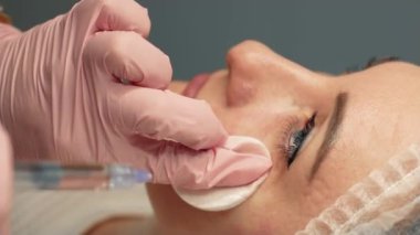Sağlık ofisindeki kadın hasta doktordan botülasyon tedavisi görüyor. Güzellik uzmanı, kadın hasta ameliyat sırasında rahat görünürken botülasyon antibiyotiği enjekte ediyor.