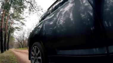 Kumlu orman yolunda araba kullanmak, ahşap alanda dönen tekerlek, alçak kamera pozisyonu. Araç gövdesine yansıyor. Kirli yolda dönen lastik. Otomobil off-road