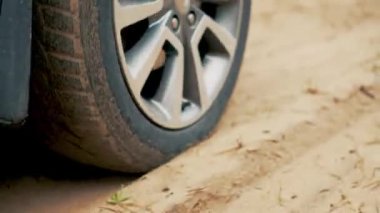 Krom tekerlek jantlı araba kumlu yol boyunca gidiyor. Yaklaş. Kirli yolda dönen lastik. Otomobil off-road