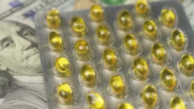 Masada dönen para ve haplar, pahalı ilaç konsepti, tedavi masrafları, sağlık sigortası. D vitamini hapları ve ilaçlar. Birleşik Devletler 'de sağlık hizmetleri maliyeti