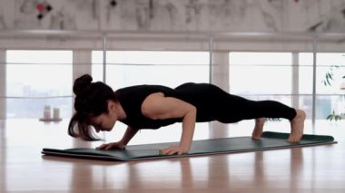 Genç atletik kız fitness stüdyosunda yoga eğitimi alıyor, tahtada duruyor. Kadın Urdhva Chaturanga Dandasana pozları veriyor. Esnek kadın stüdyoda yoga yapıyor. Fitness konsepti