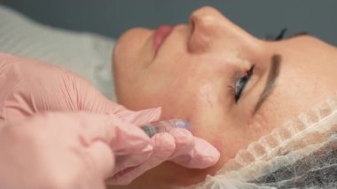 Tıp kliniğindeki doktordan güzellik aşısı alan bir kadın. Kadın hasta yüzü için şırınga kullanarak yaşlanma önleyici aşı uygulayan bir güzellik uzmanı. Kadın için yaşlanma karşıtı biyo-evyalizasyon enjeksiyonları