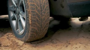 Araba tekerleği kumlu yolda yol tutuşu kazanmak için mücadele etti. Aracın dönen çarkı kapanıyor. Kirli yolda dönen lastik. Otomobil off-road