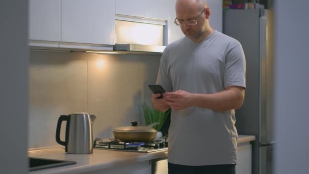 Adam Mutfakta Tavada Kızarmış Tavuk Eti Pişirirken Cep Telefonuyla Dünya — Stok video