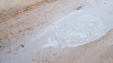 Araba su birikintisinin içinden geçiyor, farklı yönlere su ve çamur sıçratıyor. Dönen SUV lastikleri yakın plan. Kirli yolda dönen lastik. Otomobil off-road