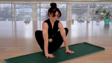 Spor giyimli genç Asyalı kadın stüdyoda yoga minderinde oturuyor. Çıplak ayaklı kadın zihinsel sağlık ve rahatlama için esneklik egzersizleri yapıyor. Spor egzersizleri ve sağlıklı yaşam tarzı için annelik kavramı